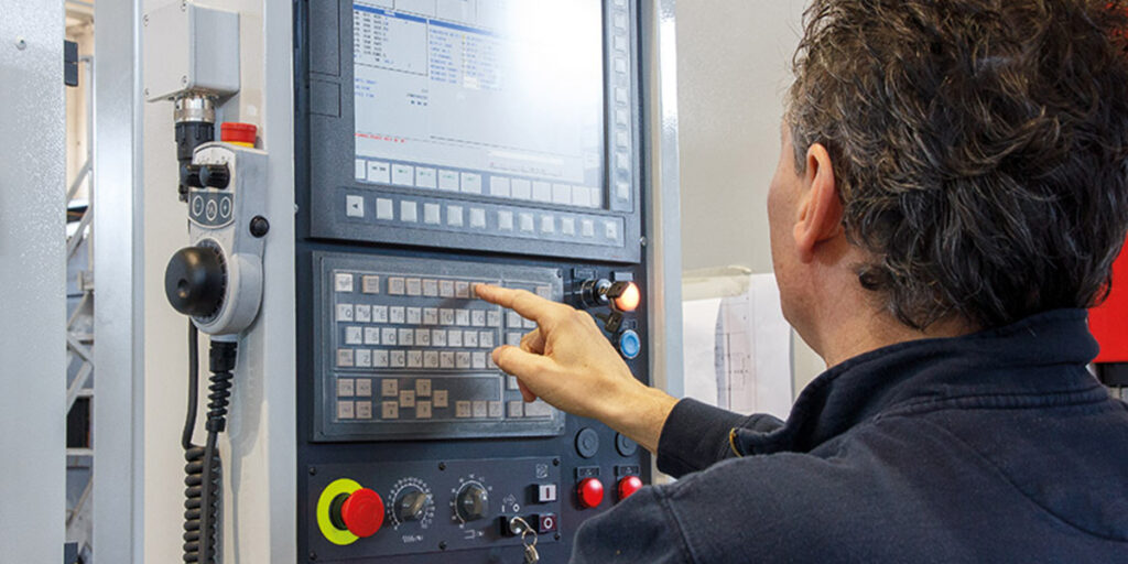 Engineers performing CNC machine programming and diagnostics